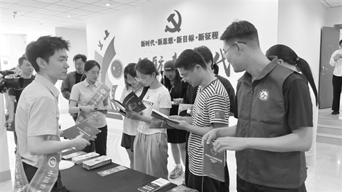 活动现场,大学生们在翻阅打击治理跨境赌博与电信诈骗宣传手册